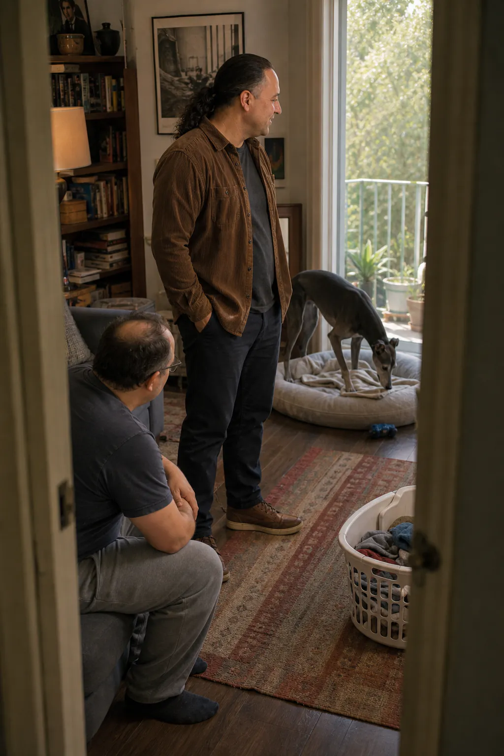 Sina Vakili and a guardian quietly observing a greyhound choosing its bed in an apartment