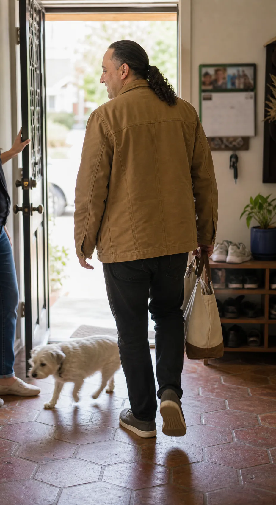 Sina Vakili walking into a client's home as a small senior terrier crosses the entry