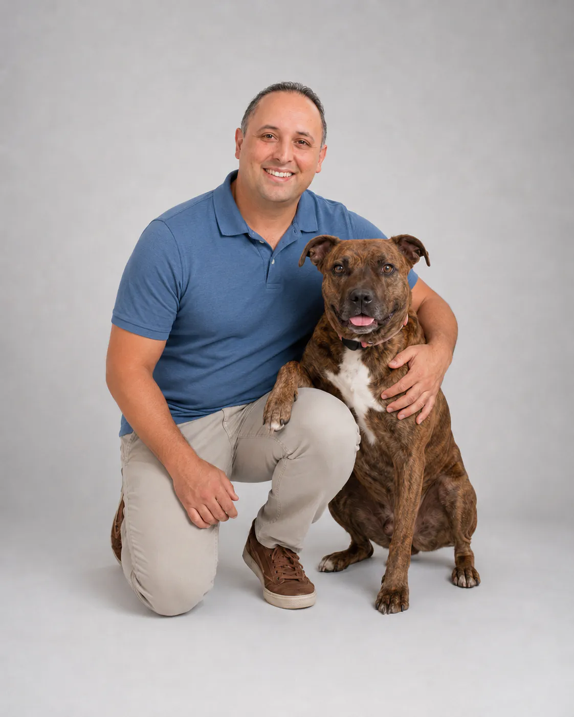 Loose Pooch founder Sina Vakili kneeling beside a brindle dog